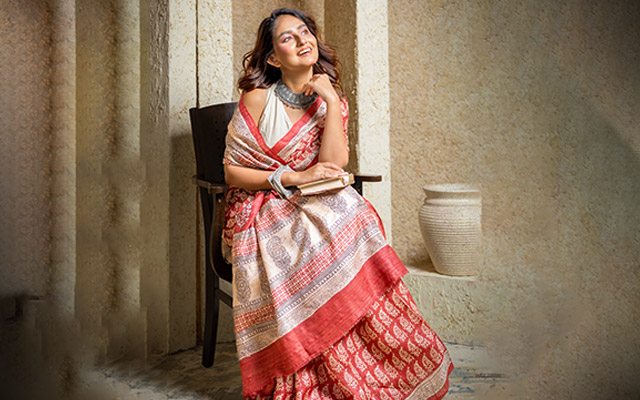 Woman wearing a red and beige printed cotton saree for a summer wedding ethnic fashion look