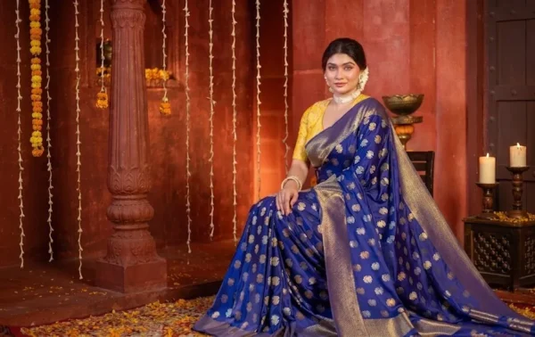A woman wearing a royal blue Banarasi silk saree with golden motifs and traditional jewellery in a festive heritage-style setting
