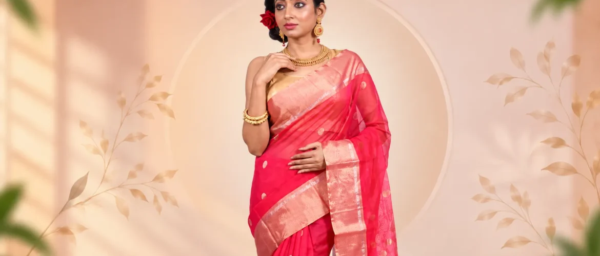 Indian woman wearing a vibrant pink silk saree with a golden zari border, styled with traditional gold jewellery for a festive ethnic look.