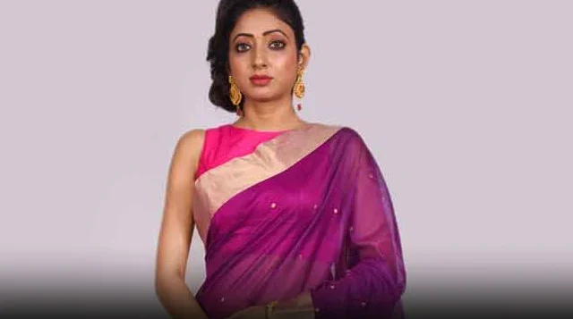 Indian woman modelling a rich purple Chanderi saree with a sleeveless pink blouse and gold dangling earrings.