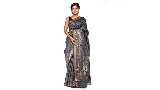 Indian woman wearing an elegant grey silk saree featuring intricate golden floral motifs, a decorative woven border and matching sleeveless blouse.